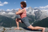 Jenny in Low Lunge (Anjaneyasana) with hands in prayer position (Namaste) at Abbott Ridge, with Mount Sir Donald in the background, Glacier National Park, B.C. (Photo by Ian Hatter)